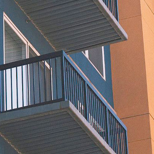 Upward view underneath balcony on a navy blue and muted orange building