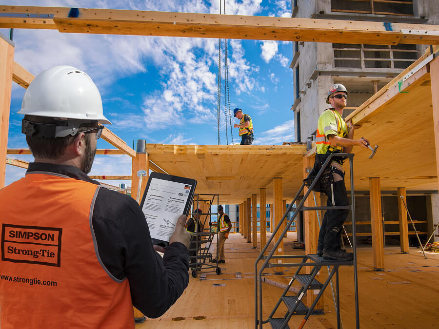 Engineer looking at tablet screen on a mass timber construction site.