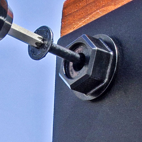 Close-up of a screwdriver fastening a hex nut into a black metal bracket.