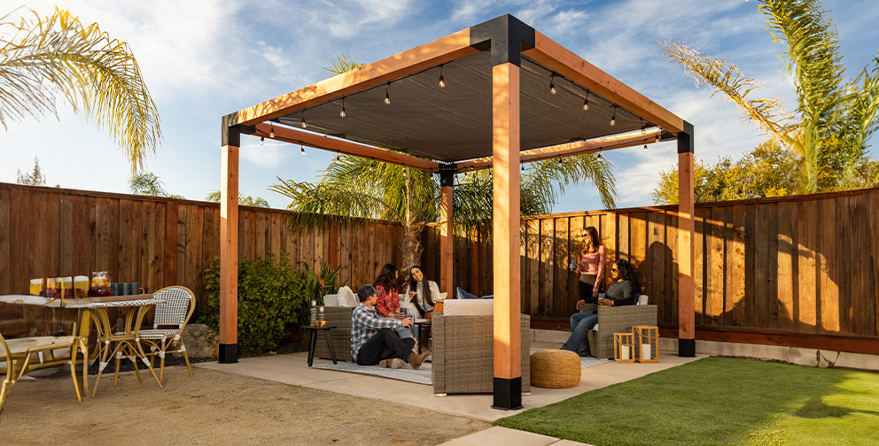 A stylish pergola with black metal accents, warm lighting, and cozy seating, creating an inviting backyard gathering space.