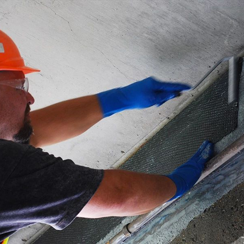 Construction worker applying FRP system to concrete wall