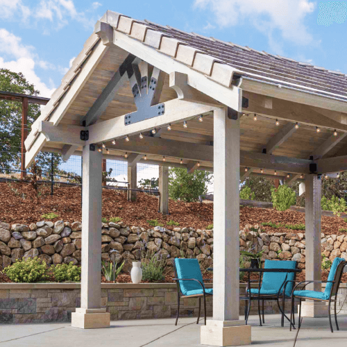 Patio table and chairs under a faux wood party pavilion.