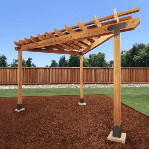 Wood three post trellis sitting on mulch in backyard.