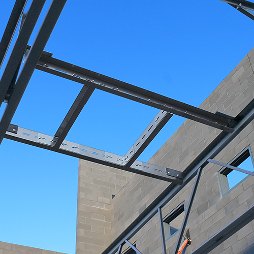 The QuickFrames™ is shown installed between concrete masonry walls, enabling fast, bolt-together structural steel framing for commercial construction.