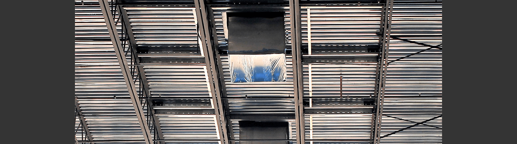 A ceiling structure with metal decking and steel framing, showing framed openings for future installations such as HVAC or skylights.
