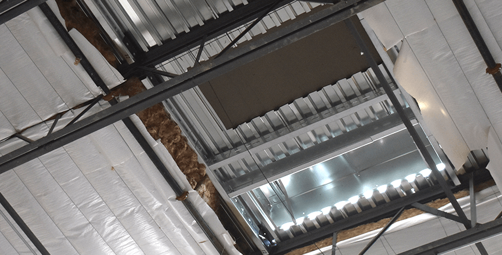 A wider view of an industrial ceiling with exposed metal framing, insulation, and a partially installed HVAC system.